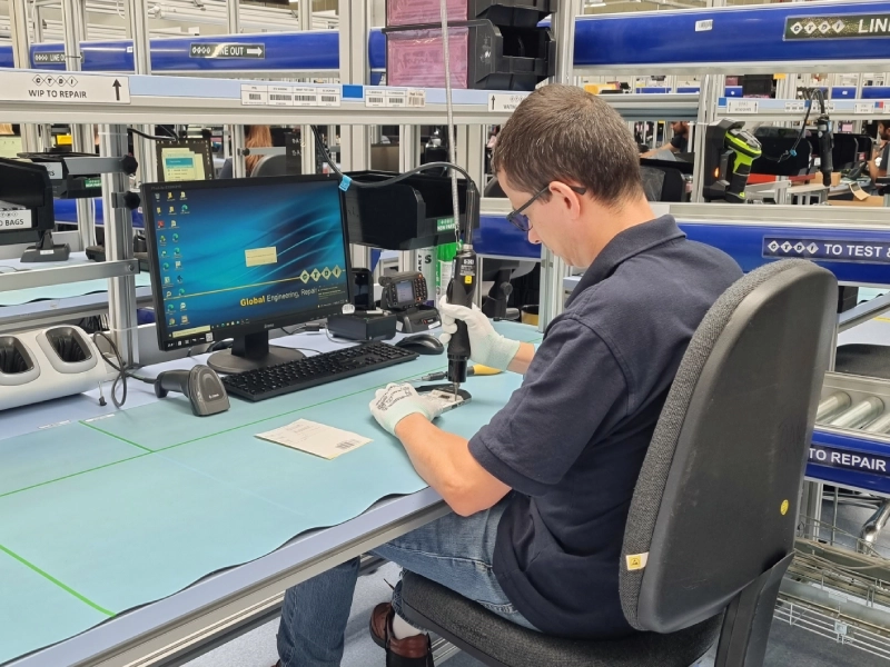 Mężczyzna pracujący przy biurku na hali produkcyjnej,naprawia urządzenie.